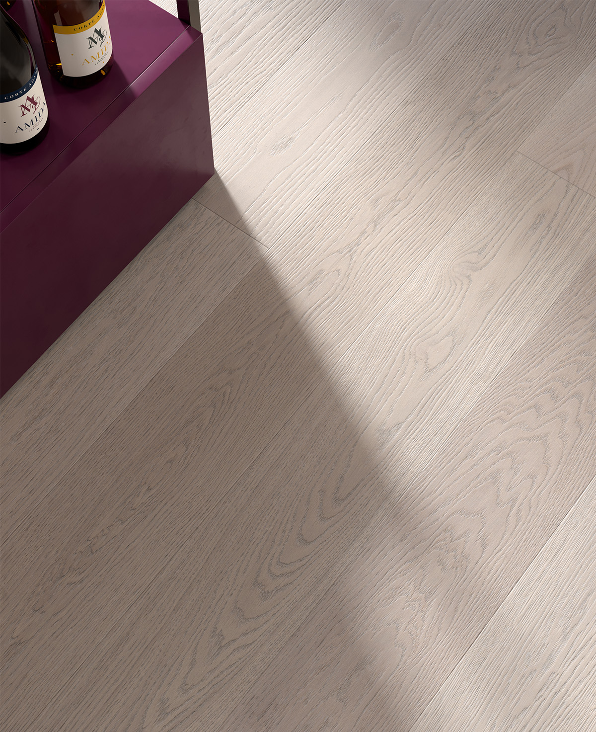 Détail du parquet en chêne gris Nebula avec veines brossées et mobilier couleur bordeaux.